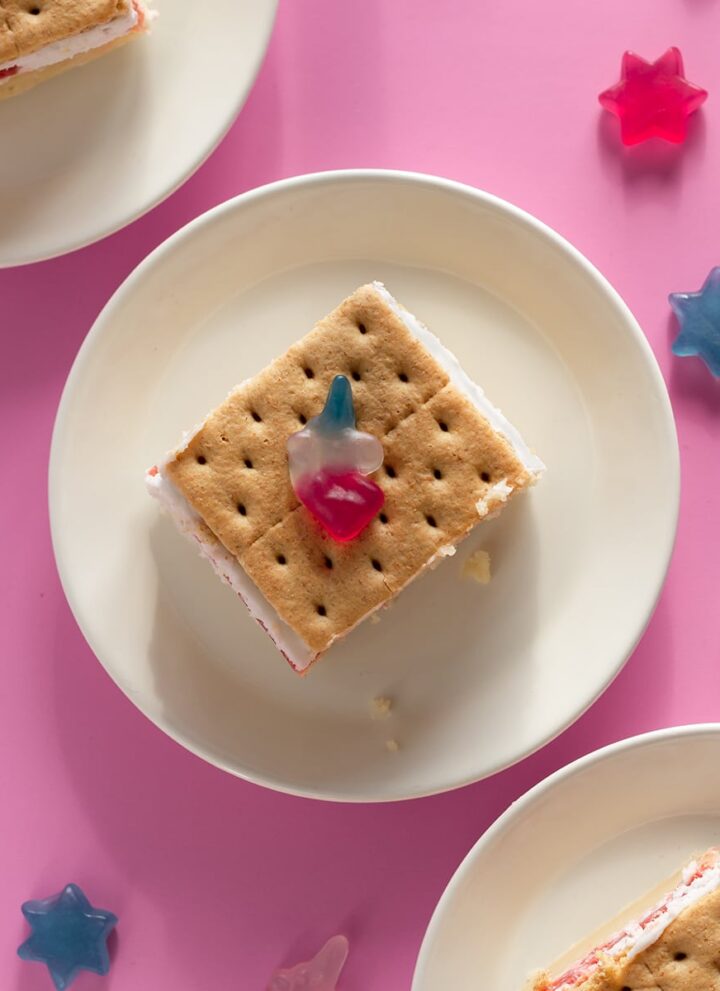 easy vegan sheet cake with strawberries and cream and graham crackers and katjes gummy candy on a white plate with pink background