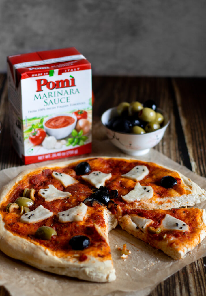 pomi marinara sauce and olives with ghost-shaped mozzarella on bread