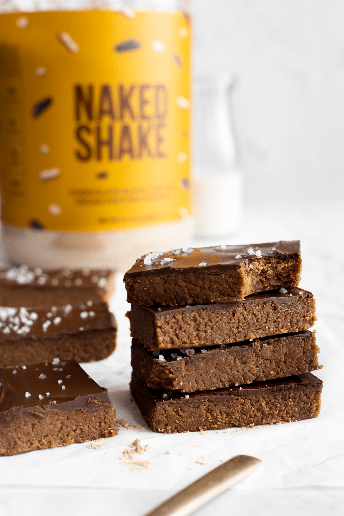 chocolate peanut butter bars stacked on top of each other with naked shake in background