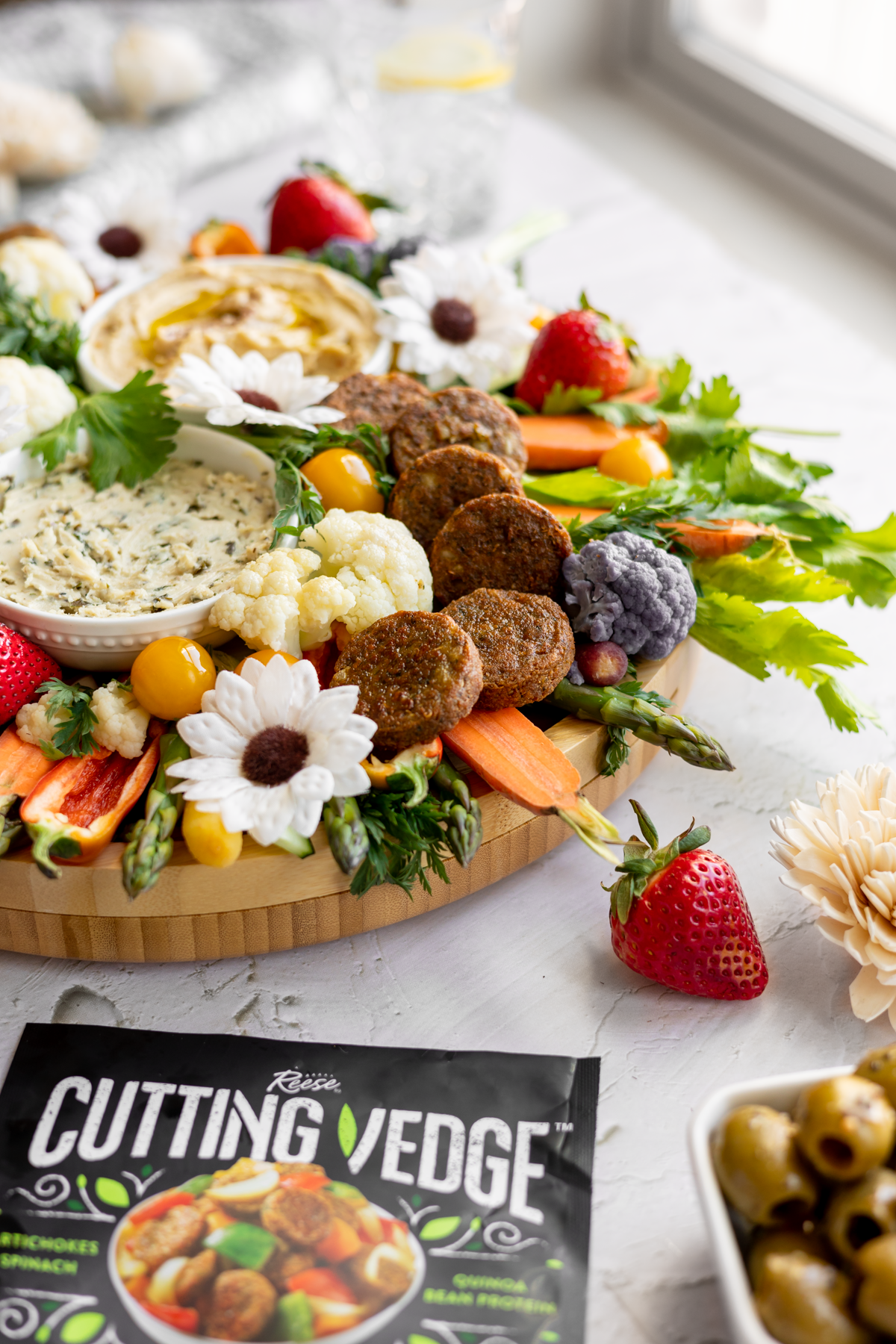 vegan spring crudité platter shown from the side with cutting vedge packaging in front of it