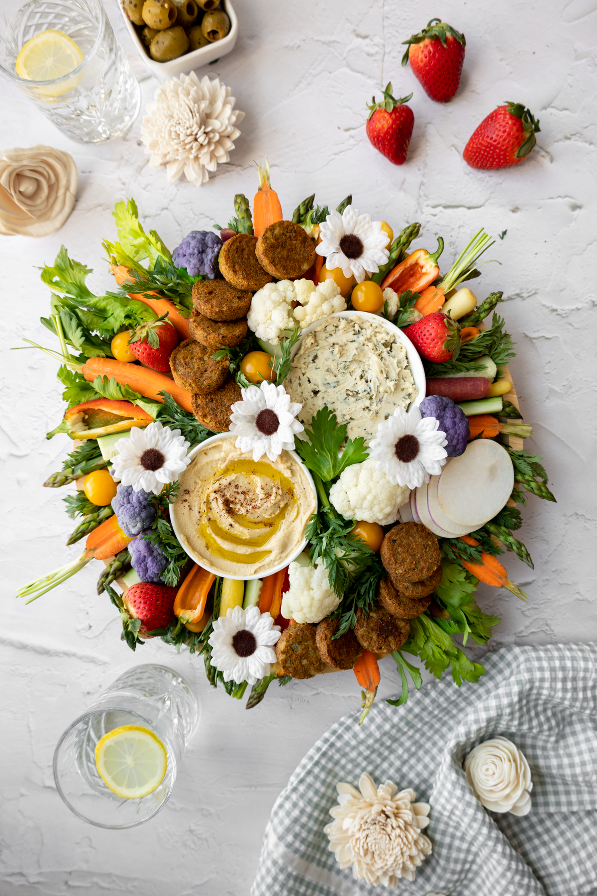 spring crudité platter assembled on a circular charcuterie board in a bright and airy setting