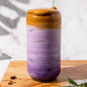 iced ube latte with frothy coffee in a latte glass in a bright and airy setting