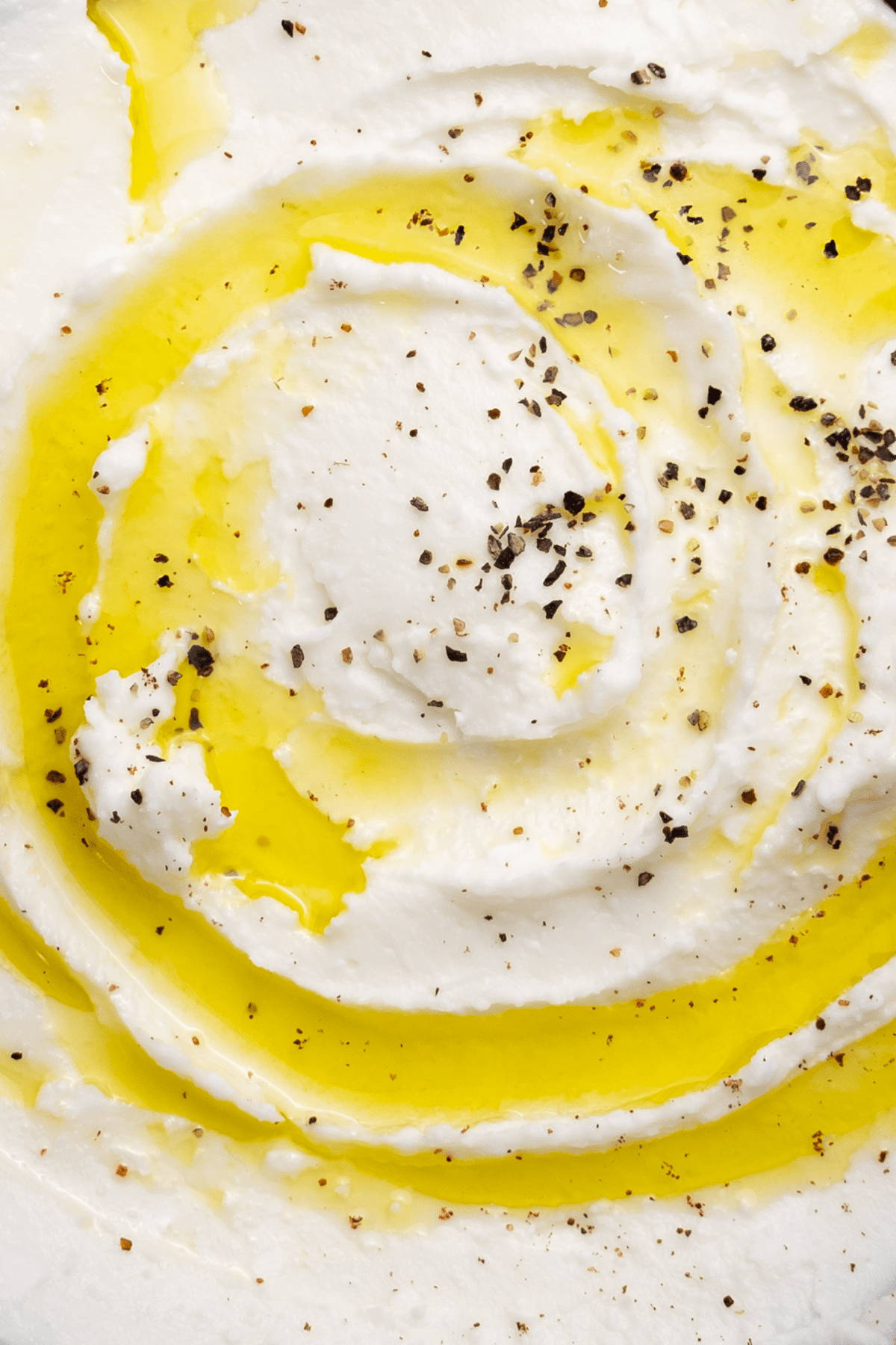 closeup of vegan whipped feta drizzled with herbs and olive oil