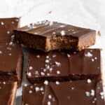 Chocolate protein peanut butter bars assembled. One bar is bitten into, showing its texture.