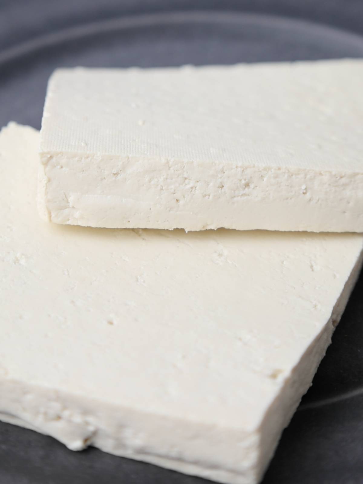 Pressed extra firm tofu block cut into two slices.