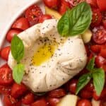 Vegan Burrata served with cherry tomatoes, fresh basil, salt, pepper, and olive oil drizzles.